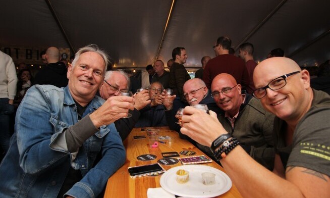 Mannen aan lange tafel proosten tijdens Bierfestival Cheers