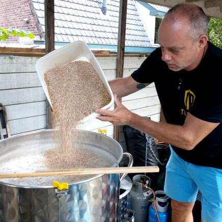 Man gooit mout in een brouwketel