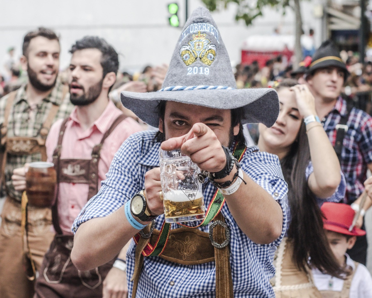 Man in traditionele Oktoberfest-kleding die met een bierpul wijst naar de camera