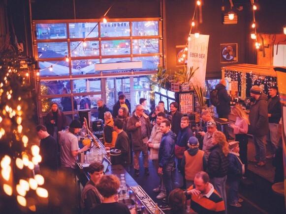 Een volle bar met mensen die drinken en met elkaar praten in een warm ruimte