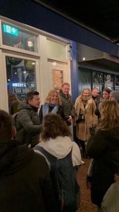 Mensen die buiten bij een horecagelegenheid staan en met elkaar praten in de avond