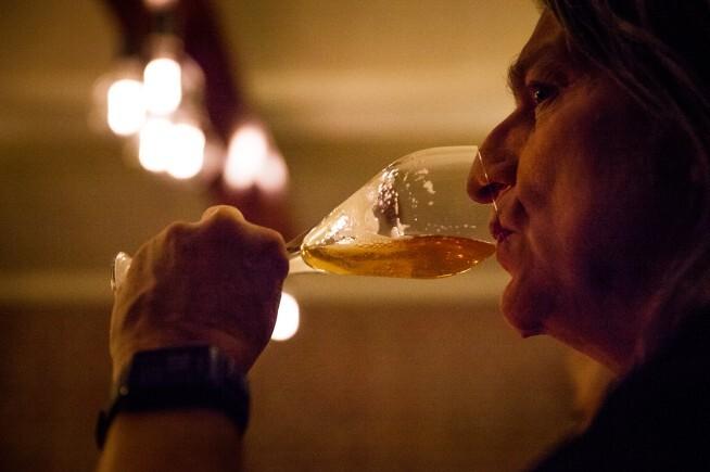 Close-up van een vrouw die bier uit een glas drinkt met zachte verlichting op de achtergrond