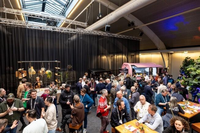 Drukke beursvloer met bezoekers die netwerken en bier proeven tijdens een bierfestival of conferentie