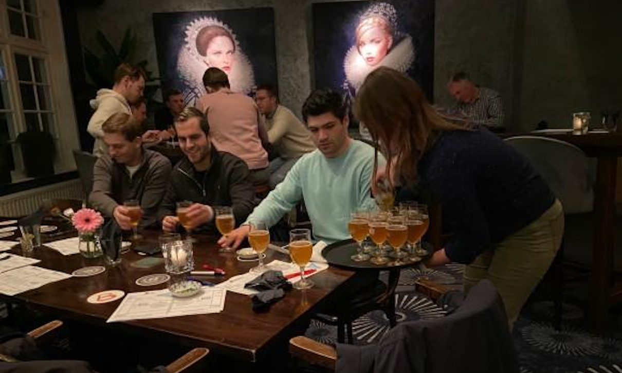 Groep mensen met bier op tafel in een sfeervol ingerichte ruimte.