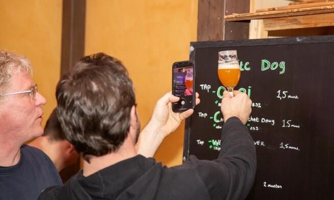 Een man fotografeert een bierglas bij een menu tijdens het Ouddorps BierFestival.