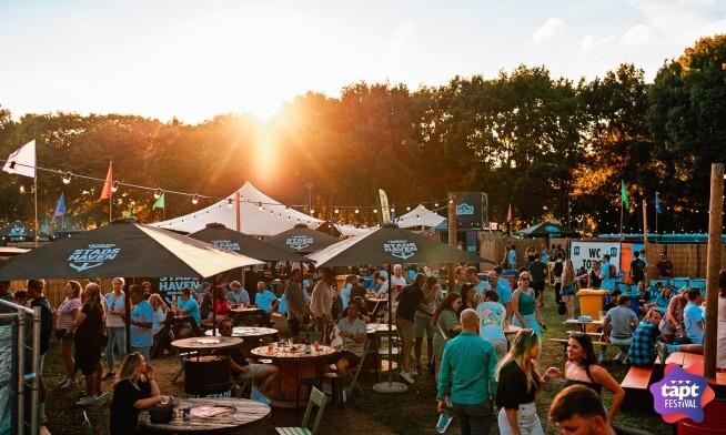 Mensen genieten van het TAPT festival in Amsterdam-West bij zonsondergang.