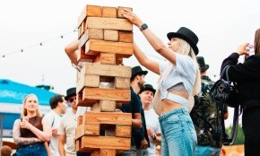 Mensen stapelen grote houten blokken tijdens buitenfestival.
