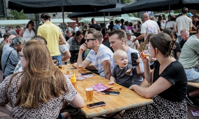 Mensen aan een biertafel genieten van het Rigters Speciaalbier Festival met drankjes.