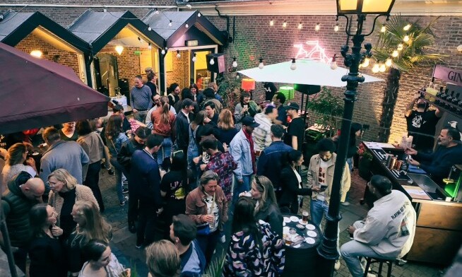 Groep mensen op een feestelijke binnenplaats onder sfeerverlichting bij avond.