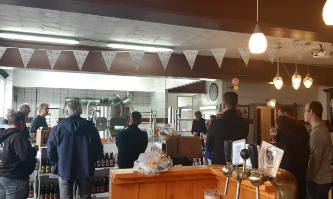 Groep mensen in een brouwerij luisteren naar uitleg over het brouwproces.