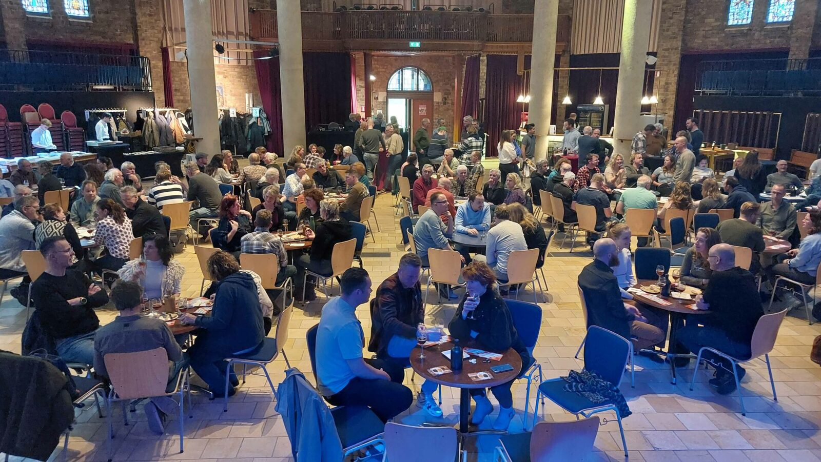 Bezoekers aan tafels in de zaal van Cultuurkoepel Heiloo tijdens de bier-kaasproeverij