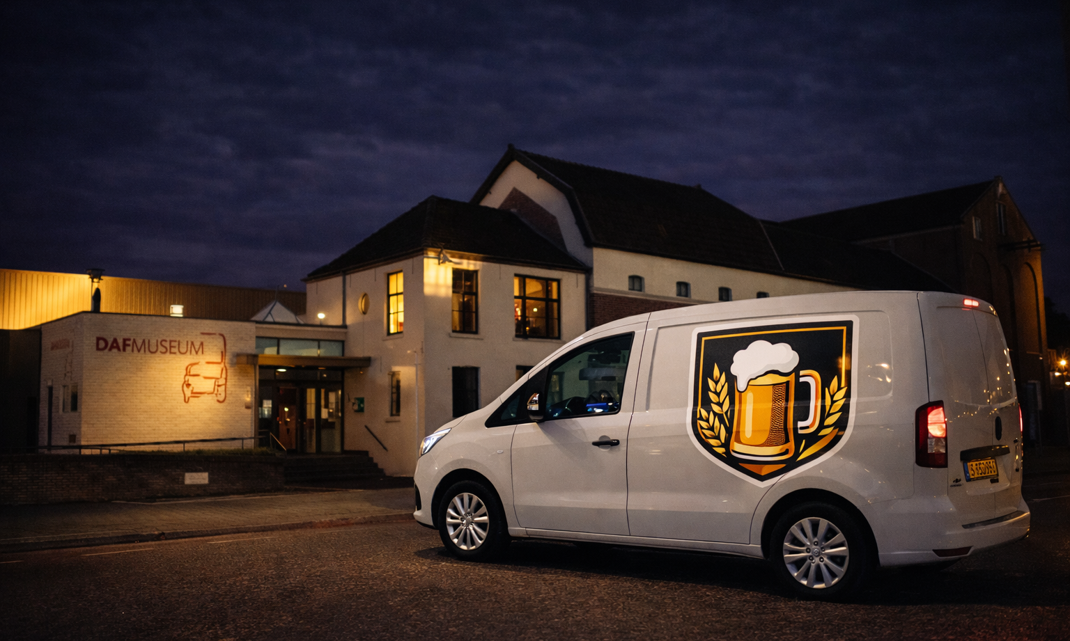 Witte bestelwagen met bierlogo geparkeerd voor het DAF Museum 's nachts.
