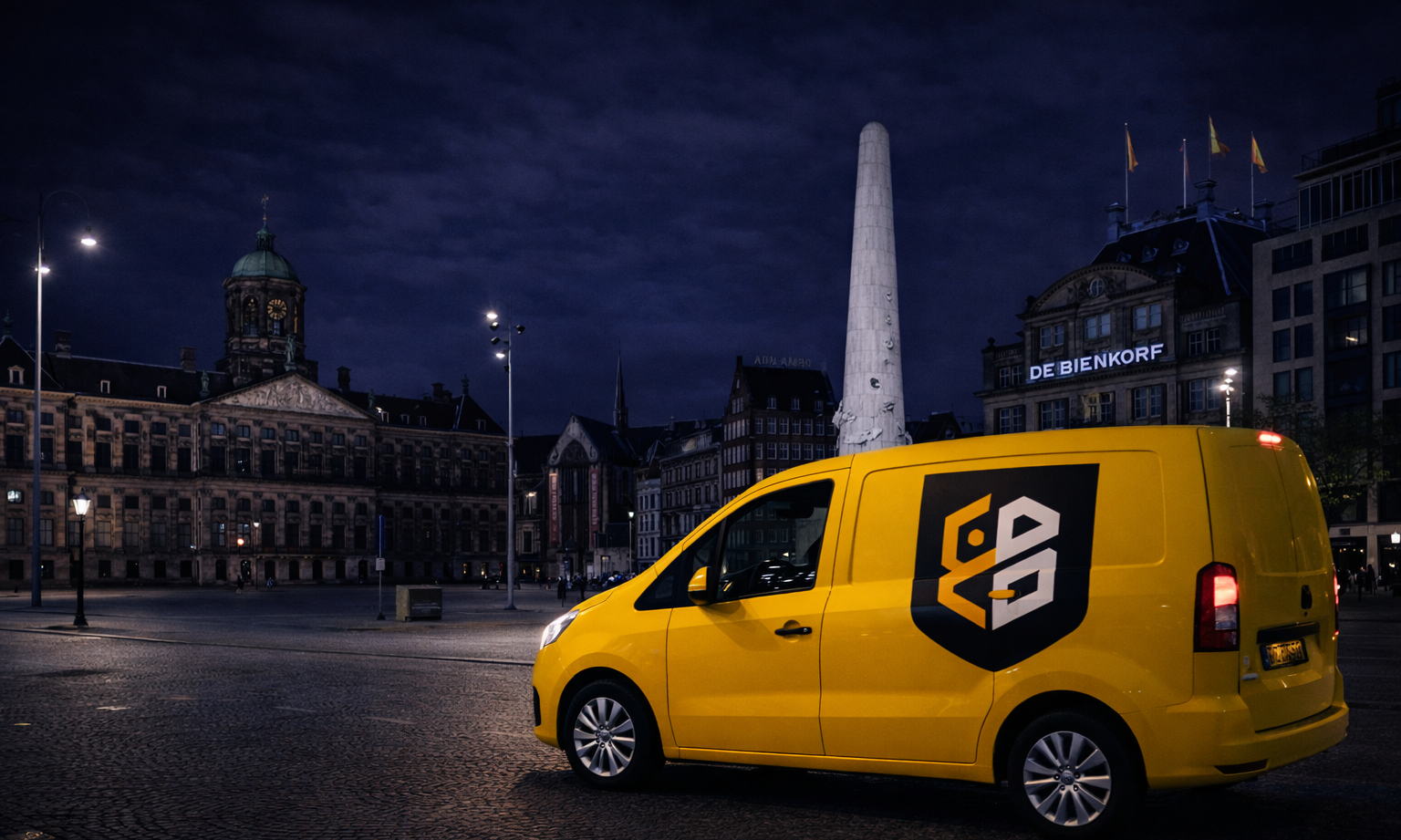 Gele bestelwagen op het lege plein van Amsterdam bij avond met verlichte gebouwen.