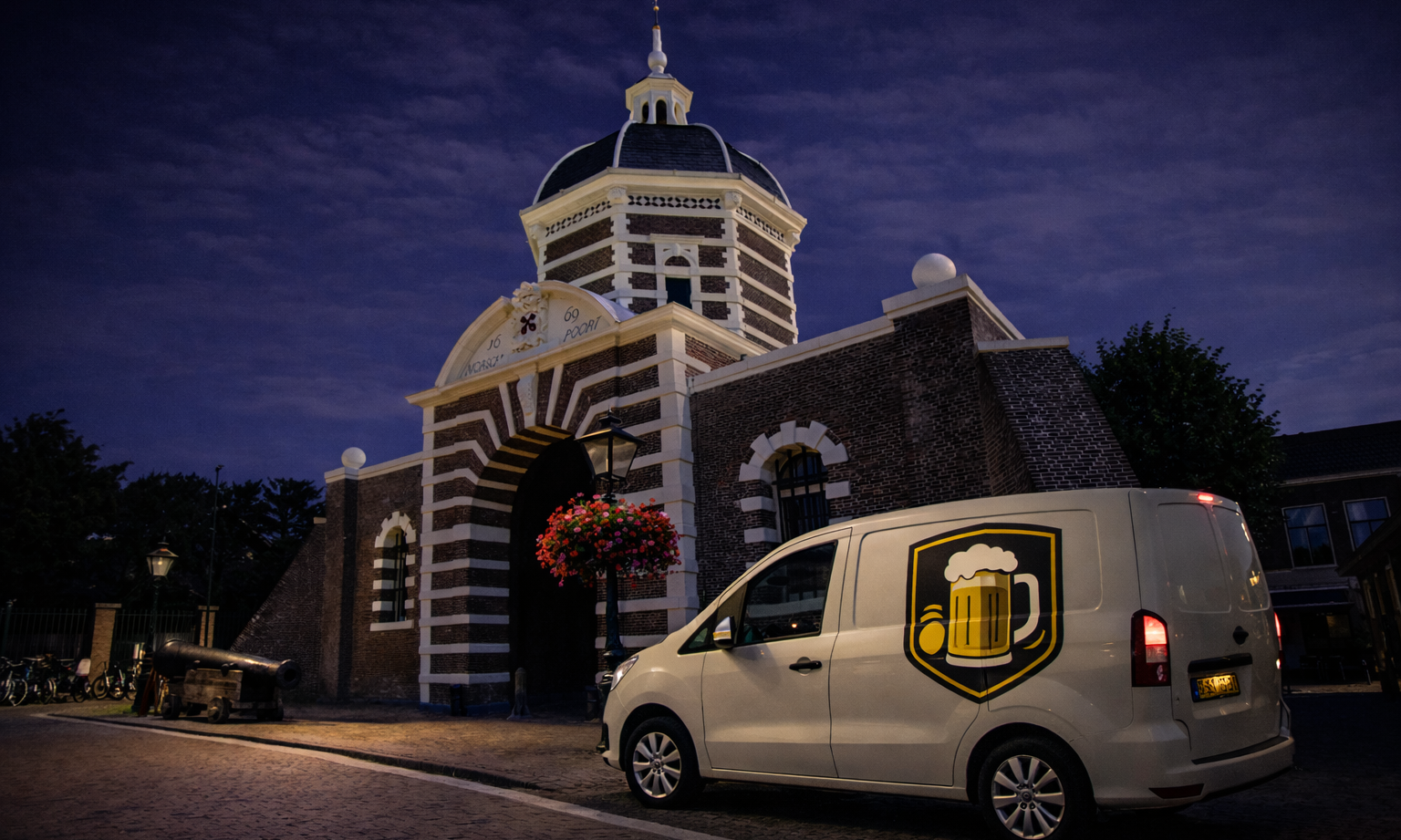 Historische poort verlicht bij schemering met bestelwagen ervoor geparkeerd