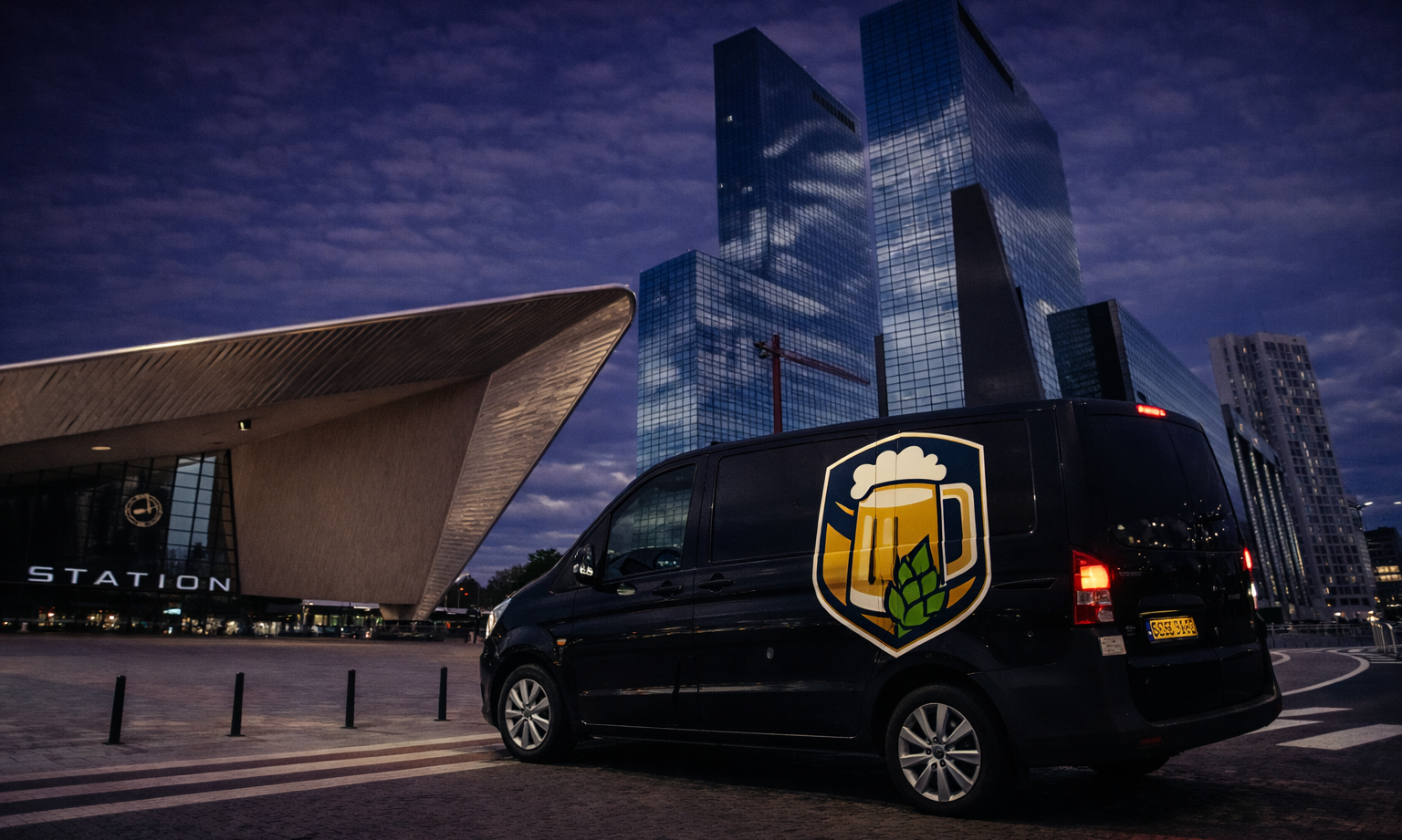 Bestelwagen met biersymbool voor modern stationsgebouw bij avond.