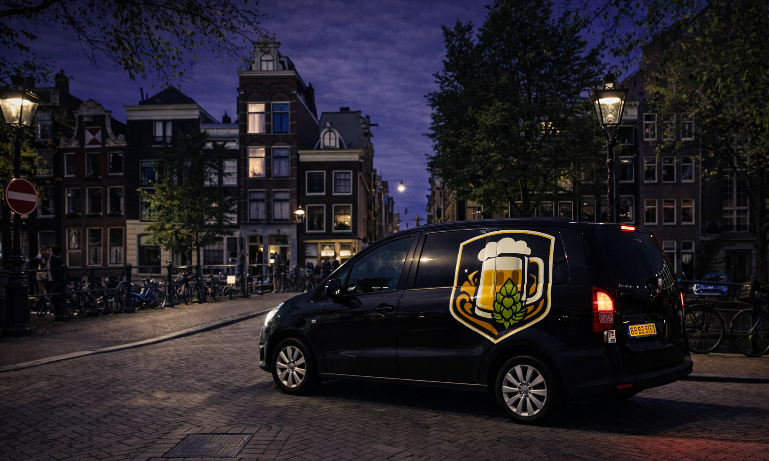 Nachtelijke straat in Amsterdam met een zwarte bestelbus aan het kanaal.