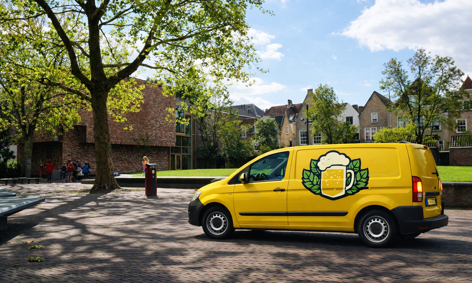 Gele bestelbus met bierlogo geparkeerd op een plein met bomen en huizen.
