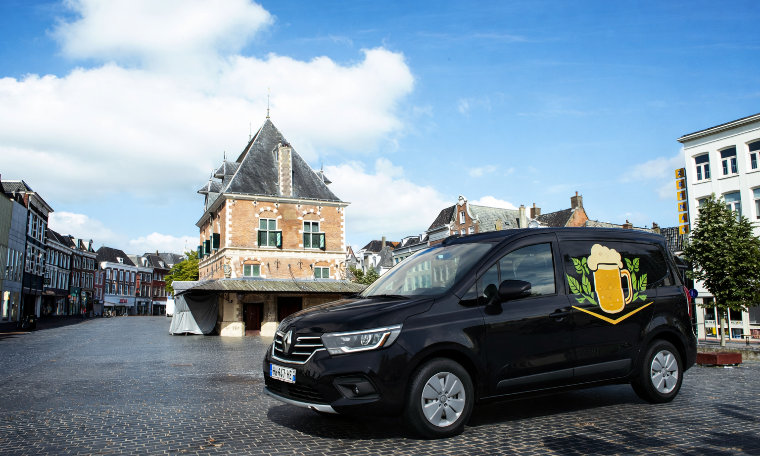 Zwarte bestelwagen met bierlogo geparkeerd op een plein voor een historisch gebouw.