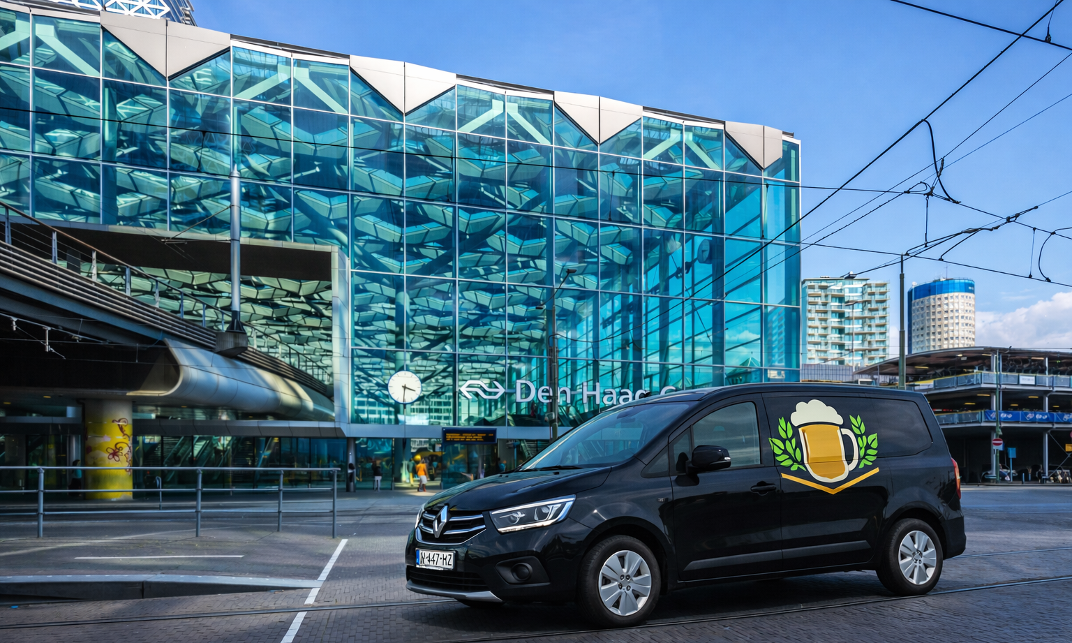 Zwarte bestelwagen met bierlogo geparkeerd voor glazen gevel van Den Haag Centraal station.