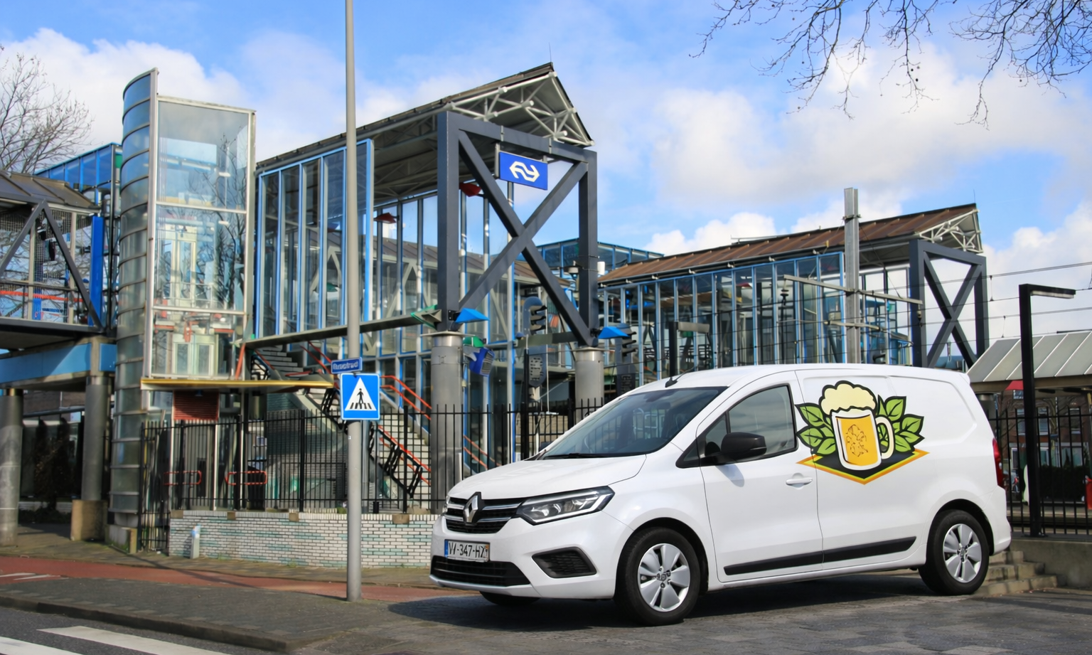 Een bestelwagen met biervatlogo geparkeerd voor een treinstation.