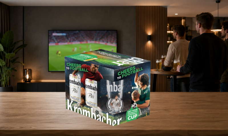 Vier mannen kijken naar een voetbalwedstrijd op tv met een doos Krombacher bier op tafel.