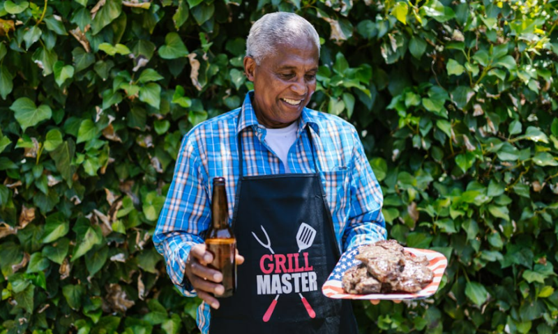 Grill Master met een biertje en vlees in de hand
