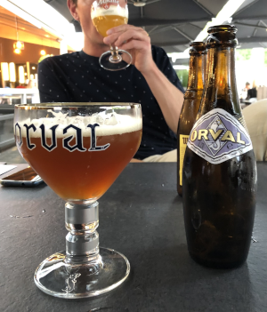 Een man drinkt ambachtelijk bier uit een glas op een terras.
