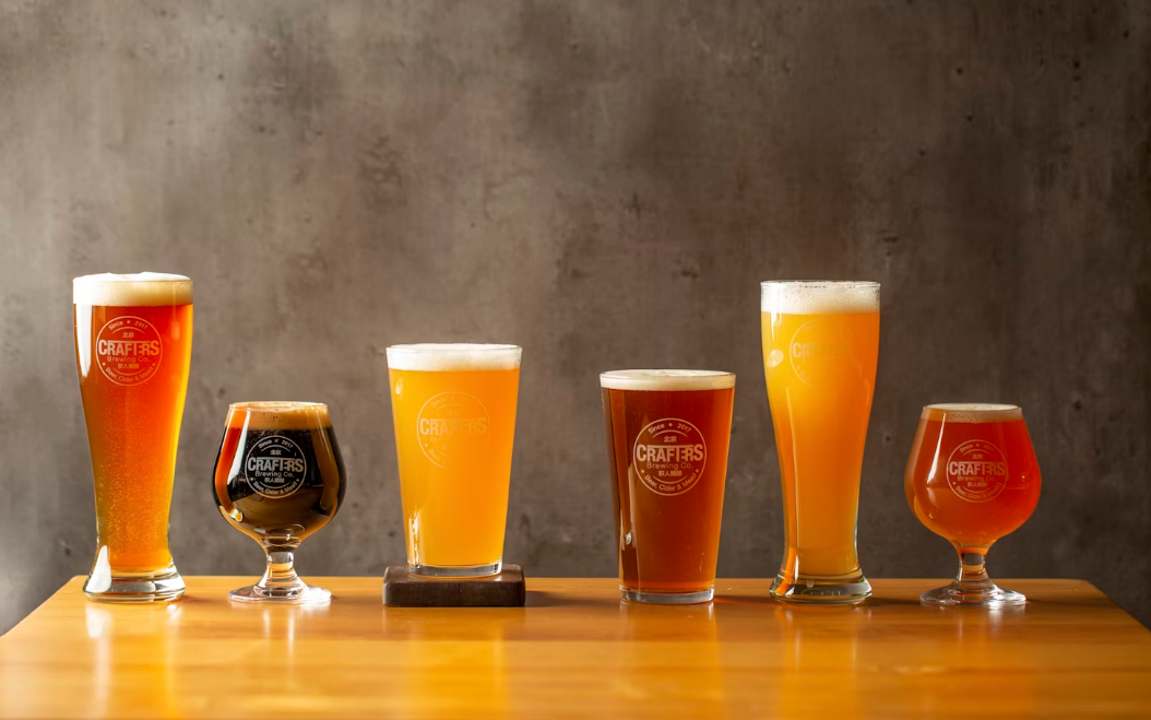 Verschillende glazen gevuld met ambachtelijk bier op een houten tafel.