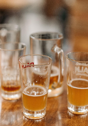 Meerdere proefglazen met bier op een houten tafel tijdens een bierproeverij.