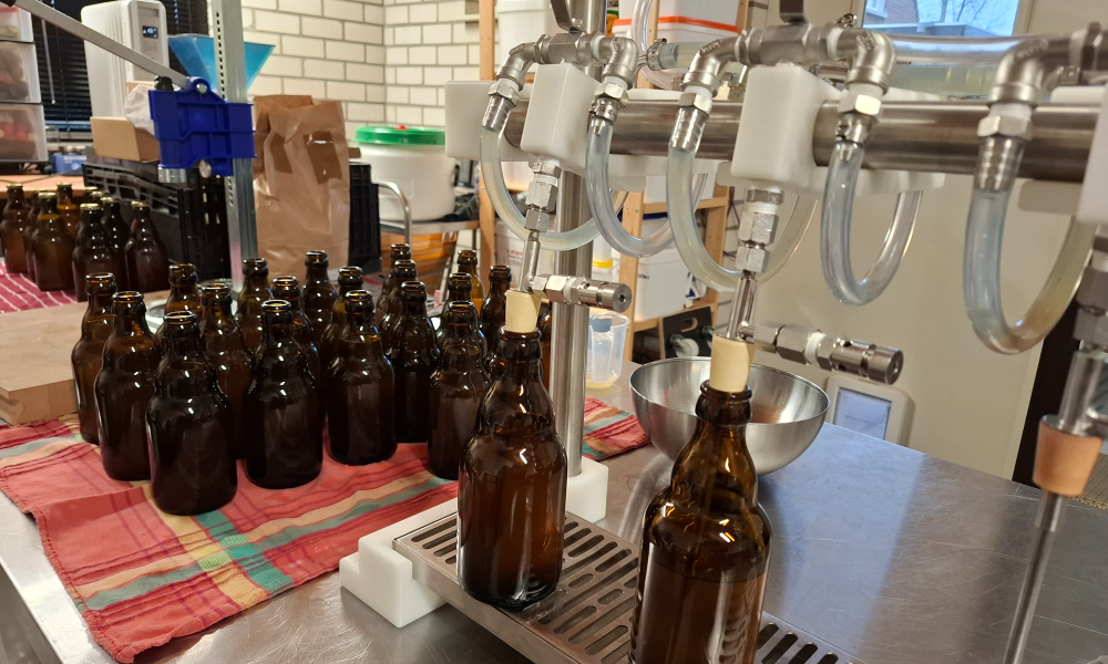 Bruine glazen flessen in een kleine bottelarij met vulmachines en een rode doek.