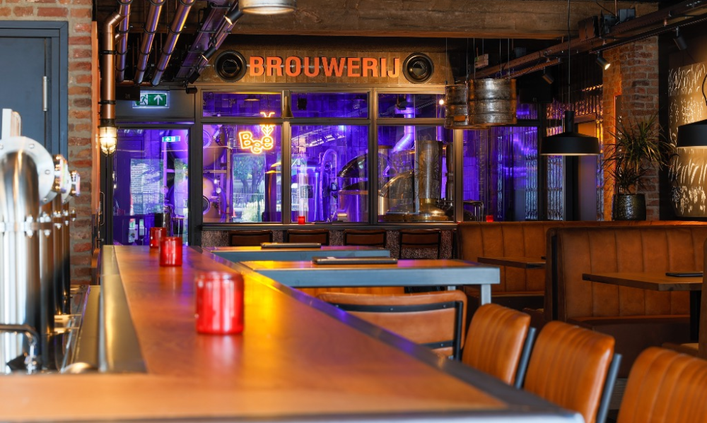 Binnenzicht van een moderne stadsbrouwerij met industriële elementen en paarse verlichting.