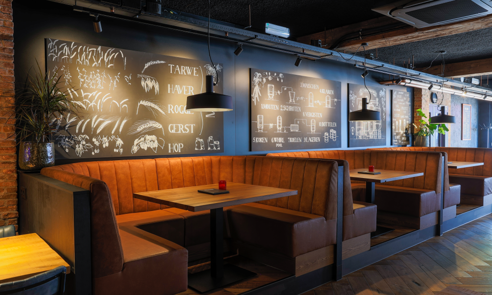 Interieur van een stijlvolle stadsbrouwerij met houten banken en decoratieve posters.
