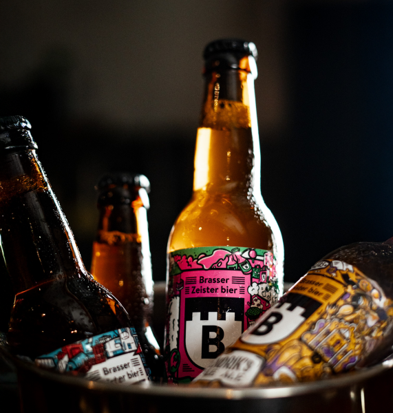 Flessen Brasser bier met kleurrijke etiketten in een emmer.