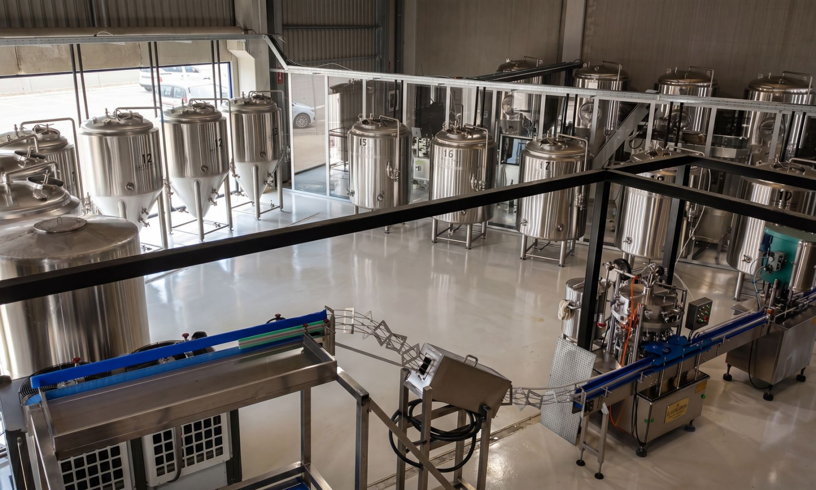 Interieur van Brouwhoeve met roestvrijstalen tanks en een afvullijn in een moderne brouwerij.