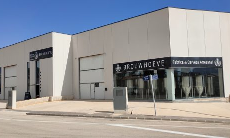Moderne brouwerij Brouwhoeve met glazen entree en zwarte gevelborden langs een straat.