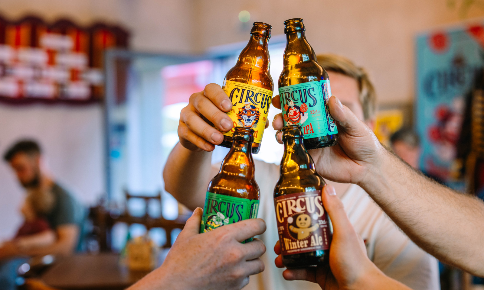 Vier handen proosten met flesjes Circus-bier in een café.