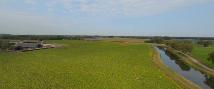 Boerderij, akker en kanaal van bovenaf gefotografeerd