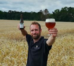Brouwer Bram met bier in de hand in een veld met graan