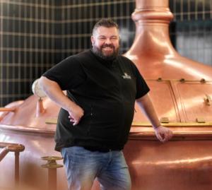 Brouwer Micha Peute voor de brouwketel in Arcen