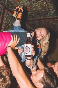 Meisje crowdsurft over mensen met een flesje Jopen Non IPA in de hand