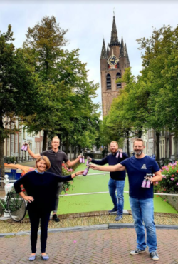 Burgermeester Marja van Bijsterveldt van Delft die het eerste flesje bier in ontvangst nam, Sander Arkenbout (Delfts Brouwhuis), Roland Dijkman (De Delft) en John Brus (Delftse Brouwers) voor een gracht in Delft met een toren op de achtergrond