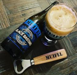 Black Bastard flesje op een tafel met een vol glas en een muifelbrouwerij opener
