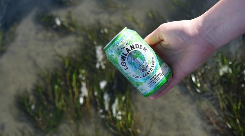 Cool Earth Lager in de hand boven zeegras