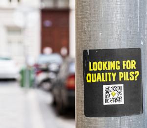 Sticker op lantaarnpaal voor quality pils tijdens ADE 2024