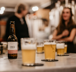 Eiber bierflesje en bierglazen met mensen op de achtergrond