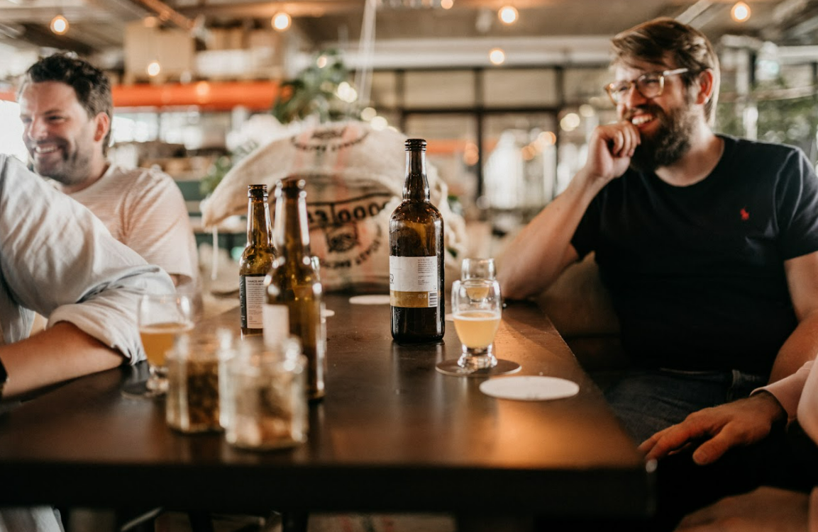 Mannen lachen aan een tafel met bier erop bij Eiber in Den Haag