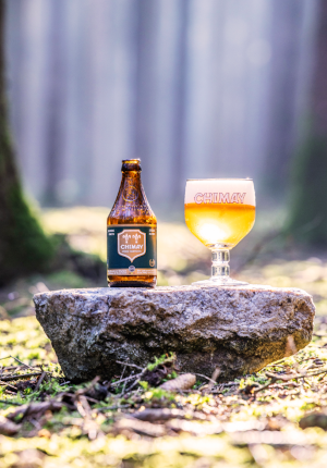 Chimay 150 flesje en glas op een steen in het bos