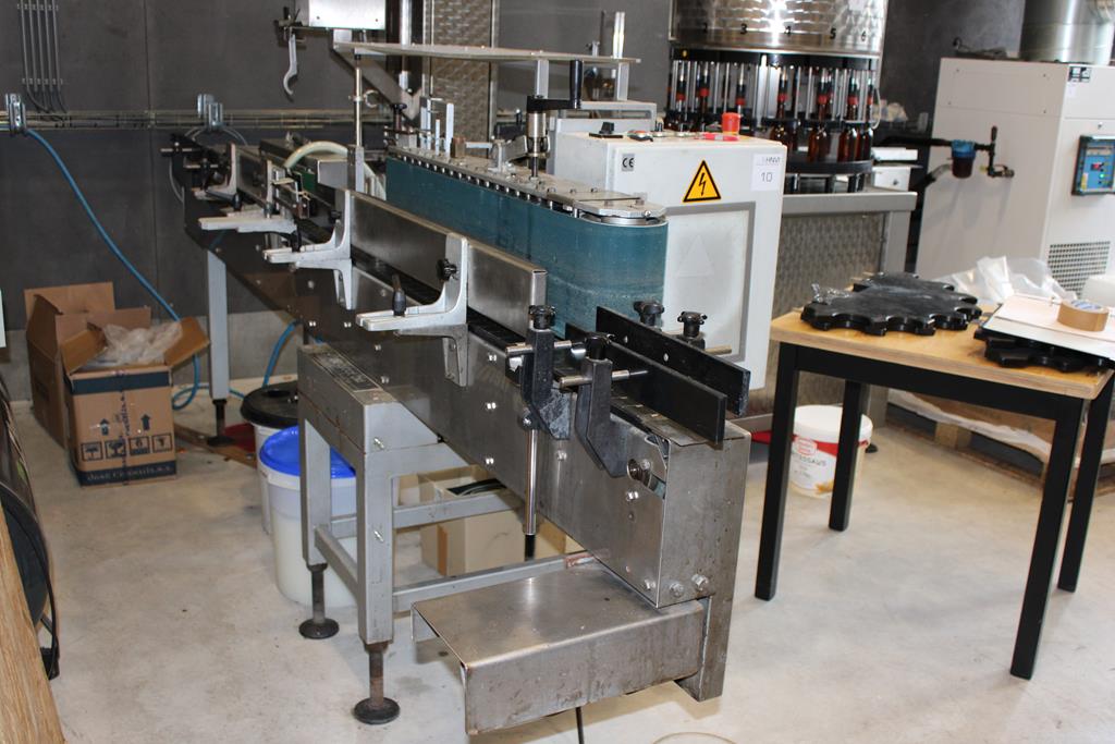 Zijaanzicht van de flessenafvulmachine met transportband en etiketteermachine