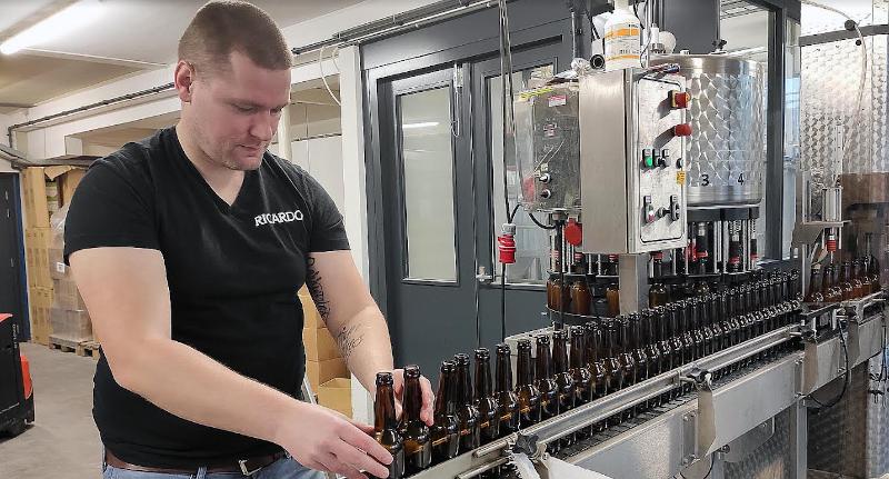 De lege flessen worden op de band gezet van de vulmachine.