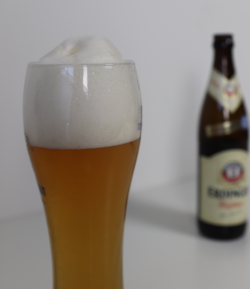 Duits Weizen bier Duits Weizen bier schuimkraag met een flesje Erdinger Hefe Weisse op de achtergrond